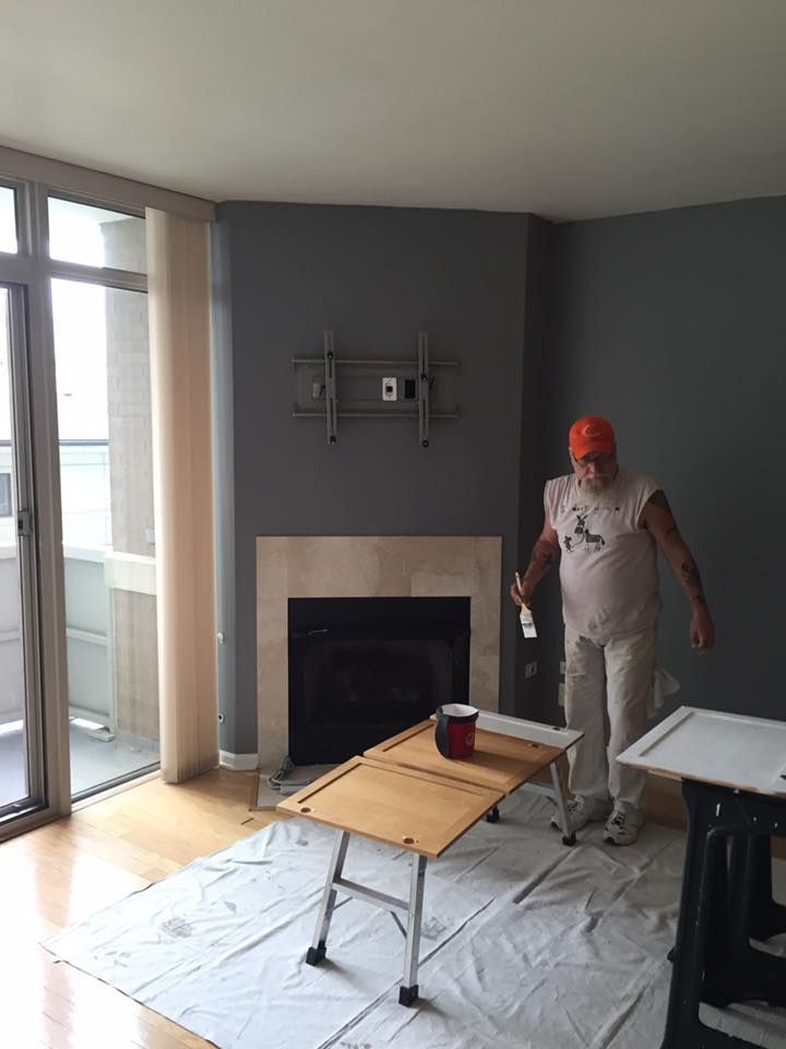 A man is painting a fireplace in a living room.