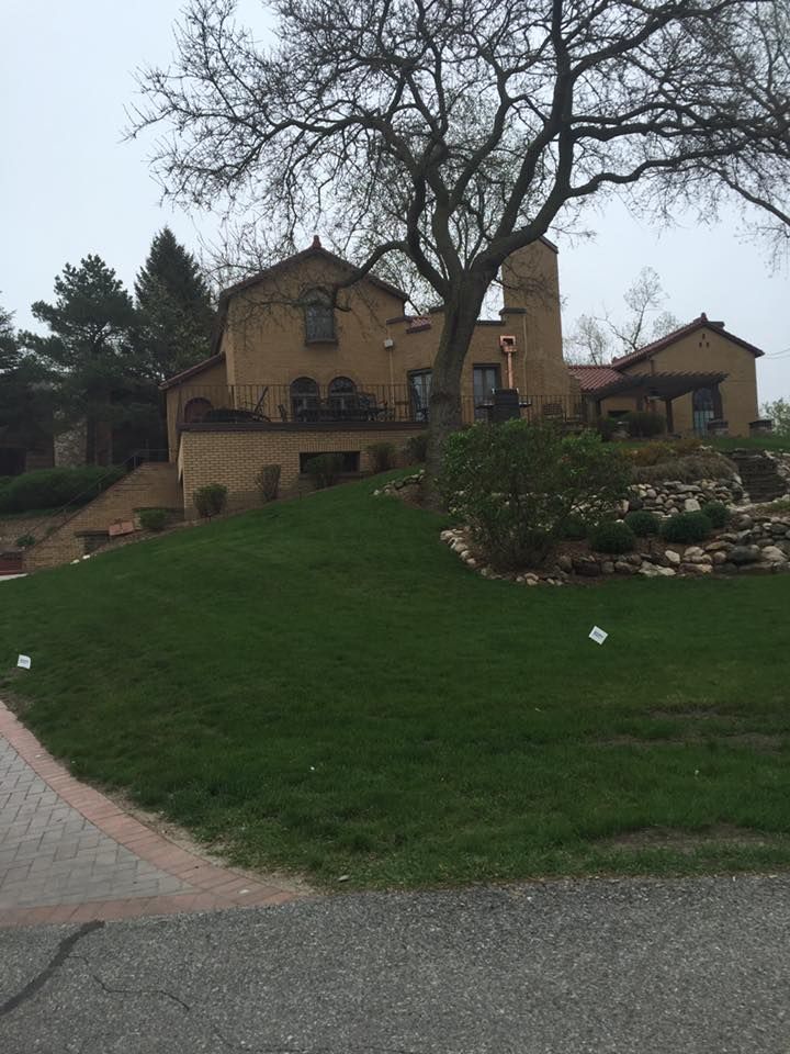 A Large House Sits On Top Of A Grassy Hill