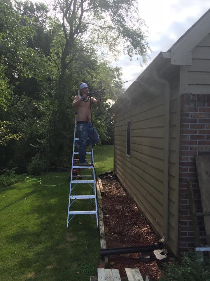 A Man Standing On A Ladder In Front Of A House