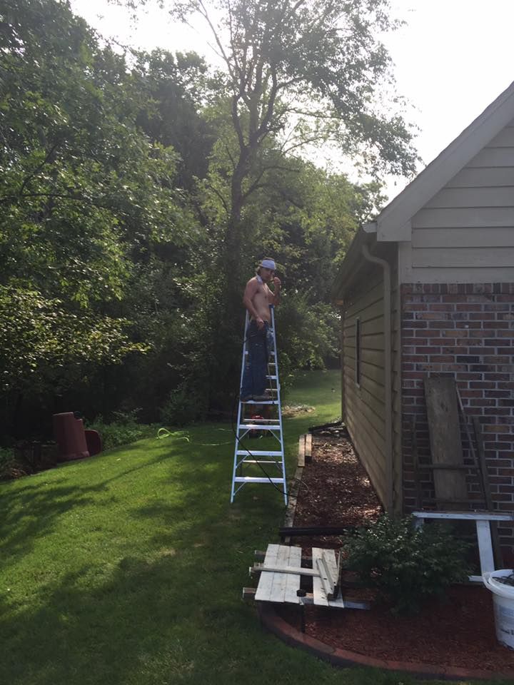 A Man Standing On A Ladder In Front Of A House