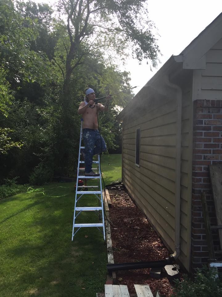 A Man Standing On A Ladder In Front Of A House