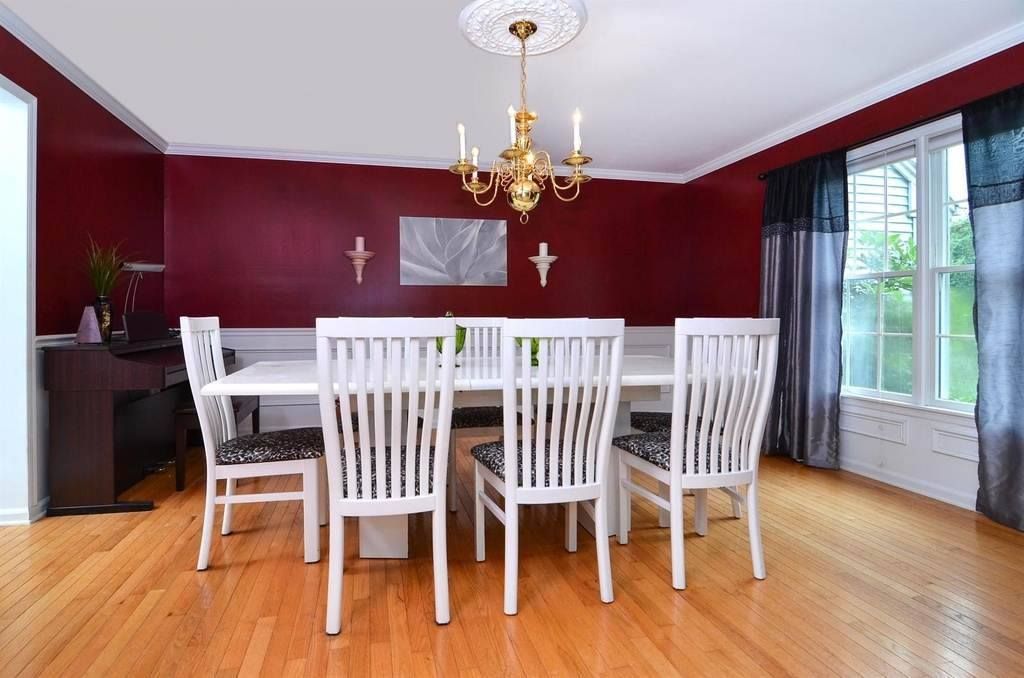 A dining room with red walls and white chairs