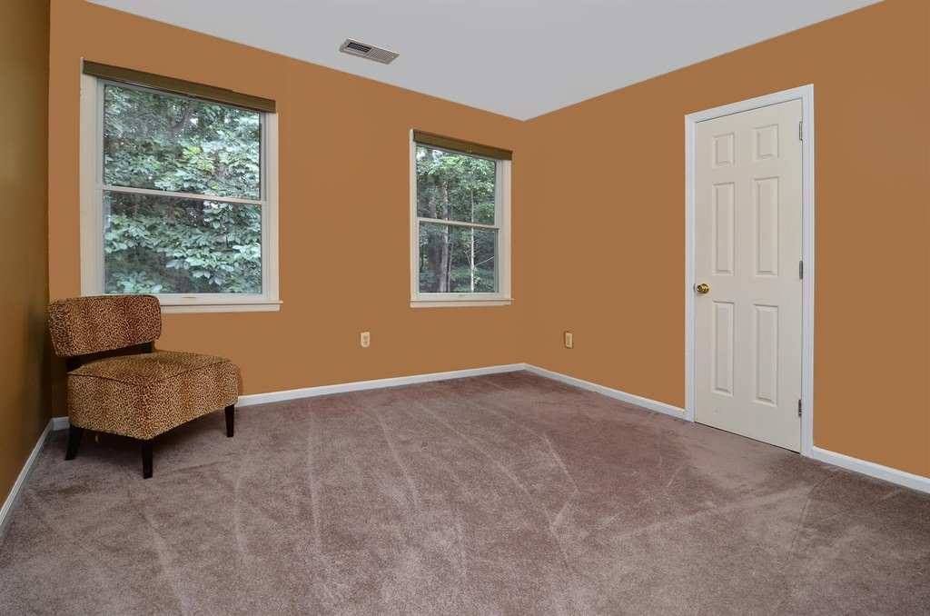 An Empty Room With A Chair And Two Windows