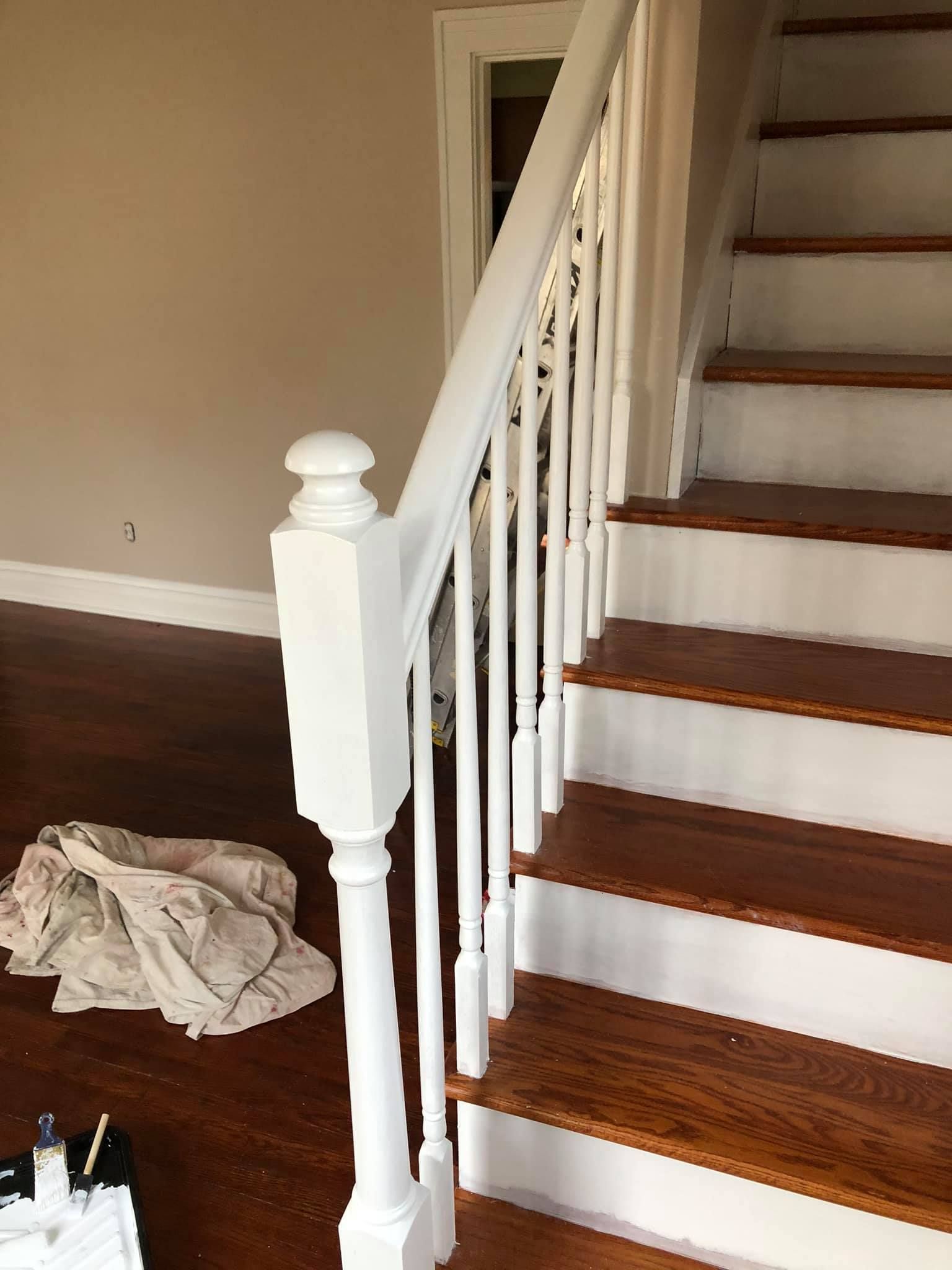 A white railing on a set of wooden stairs in a house.