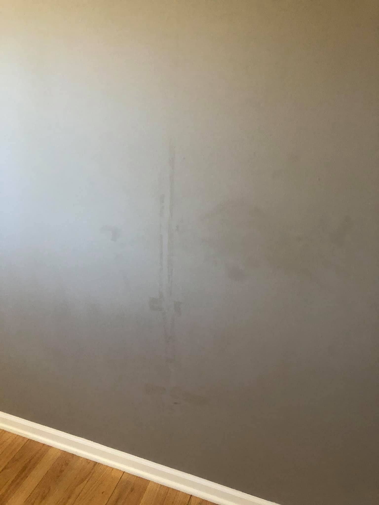 A room with a gray wall and a wooden floor.