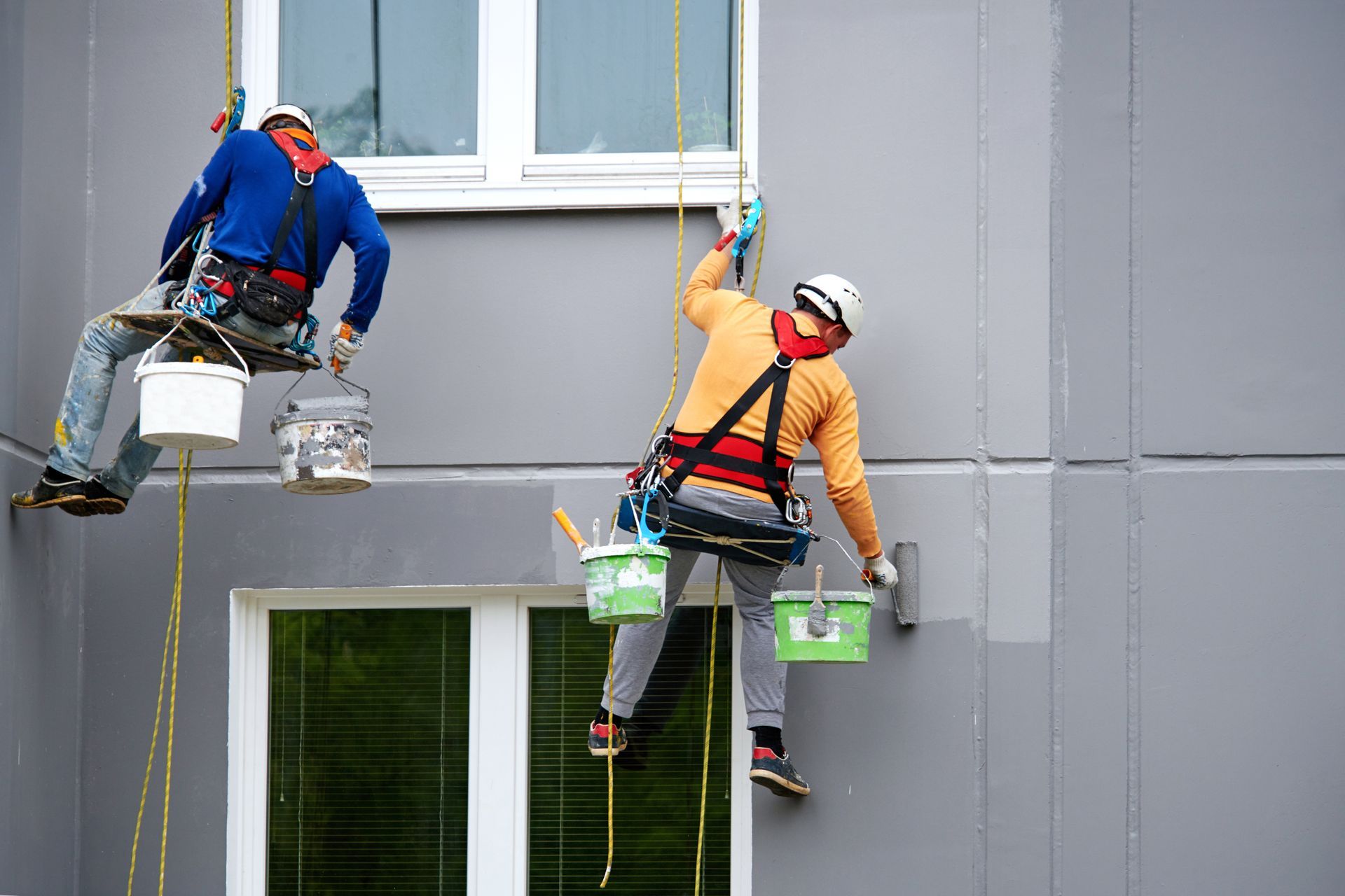 Two men are painting the side of a building.