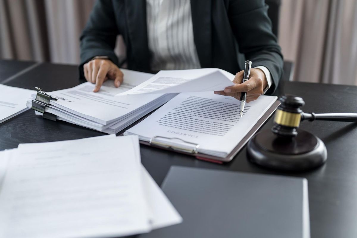 Person reviewing paperwork at a desk beside a gavel and open notebook