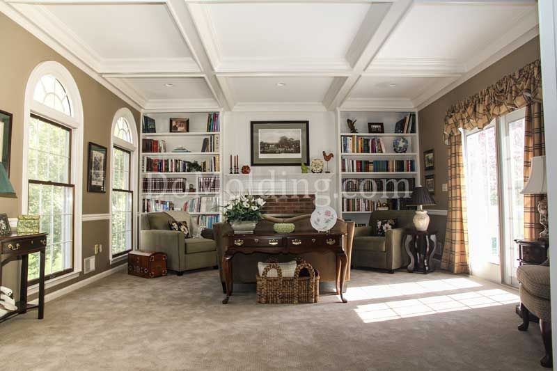 A well-lit home office with built-in bookshelves, arched windows, and a wooden desk.