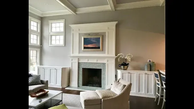 Living room with fireplace, artwork, white trim, gray walls, and comfortable seating.