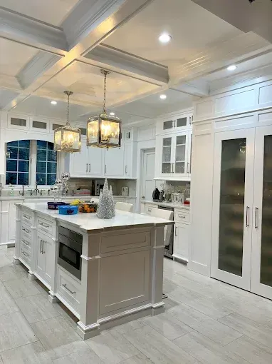 Bright white kitchen with island, cabinets, and two hanging pendant lights.