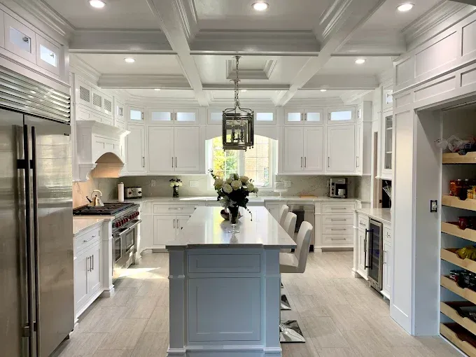 Bright white kitchen with island, cabinets, stainless steel appliances, and wood-look flooring.