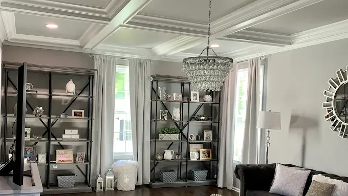 Living room with gray walls, bookshelves, a chandelier, and windows.