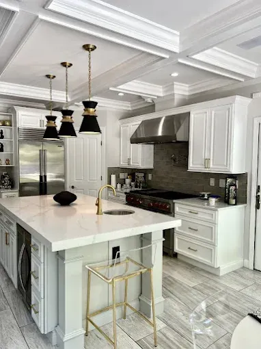 Elegant white kitchen with island, gold accents, and decorative ceiling.