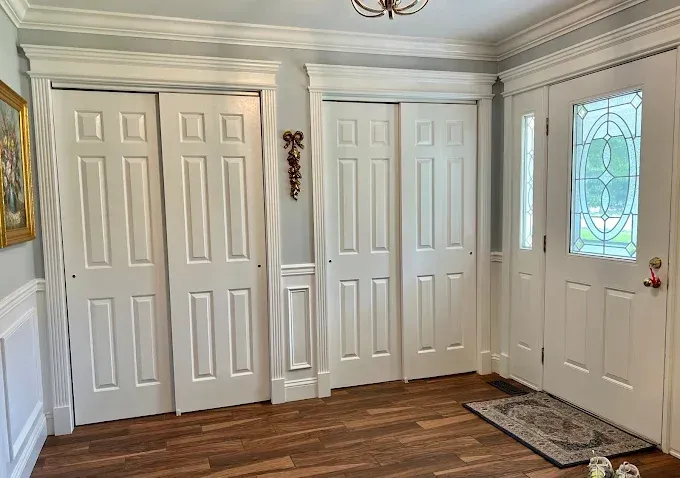 Entryway with two closets, a decorative door, and hardwood floors. White doors and trim.
