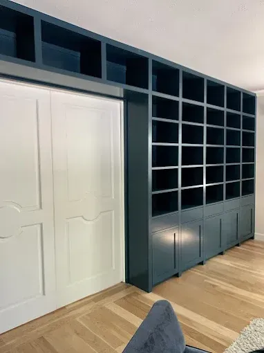 Built-in blue bookshelf with white sliding doors, on a hardwood floor.