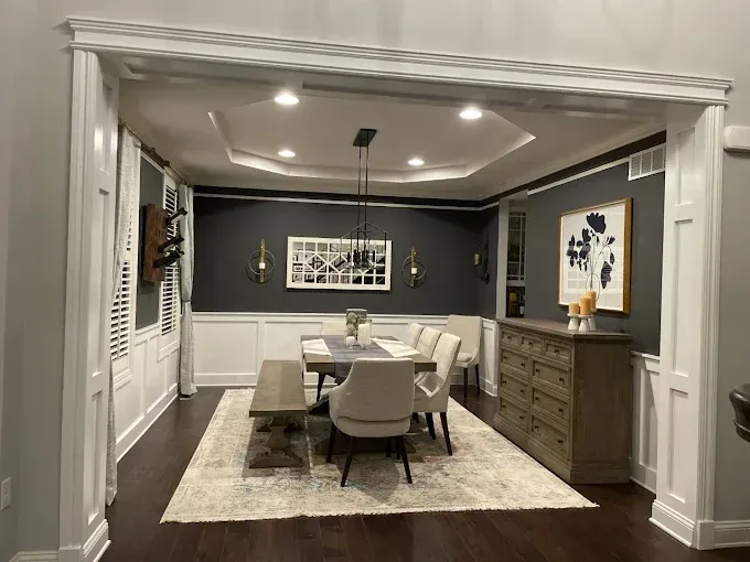 Formal dining room with dark gray walls, white trim, and a table set for a meal.