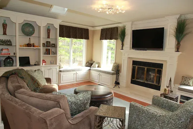 Living room with built-ins, fireplace, window seat, two sofas, and an armchair.