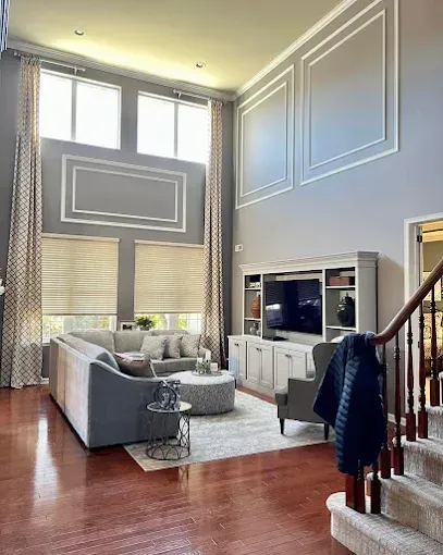 Spacious living room with gray walls, large windows, a sectional sofa, and a built-in entertainment center.