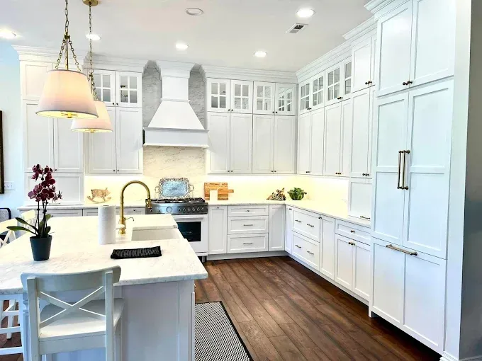 White kitchen with island, cabinets, gold hardware, and wood floors.