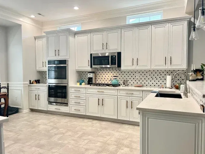 White kitchen with stainless steel appliances, white cabinets, and black and white backsplash.