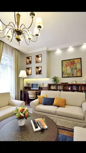 Cozy living room with cream-colored sofa, round table, desk, built-in shelves, and ornate chandelier.