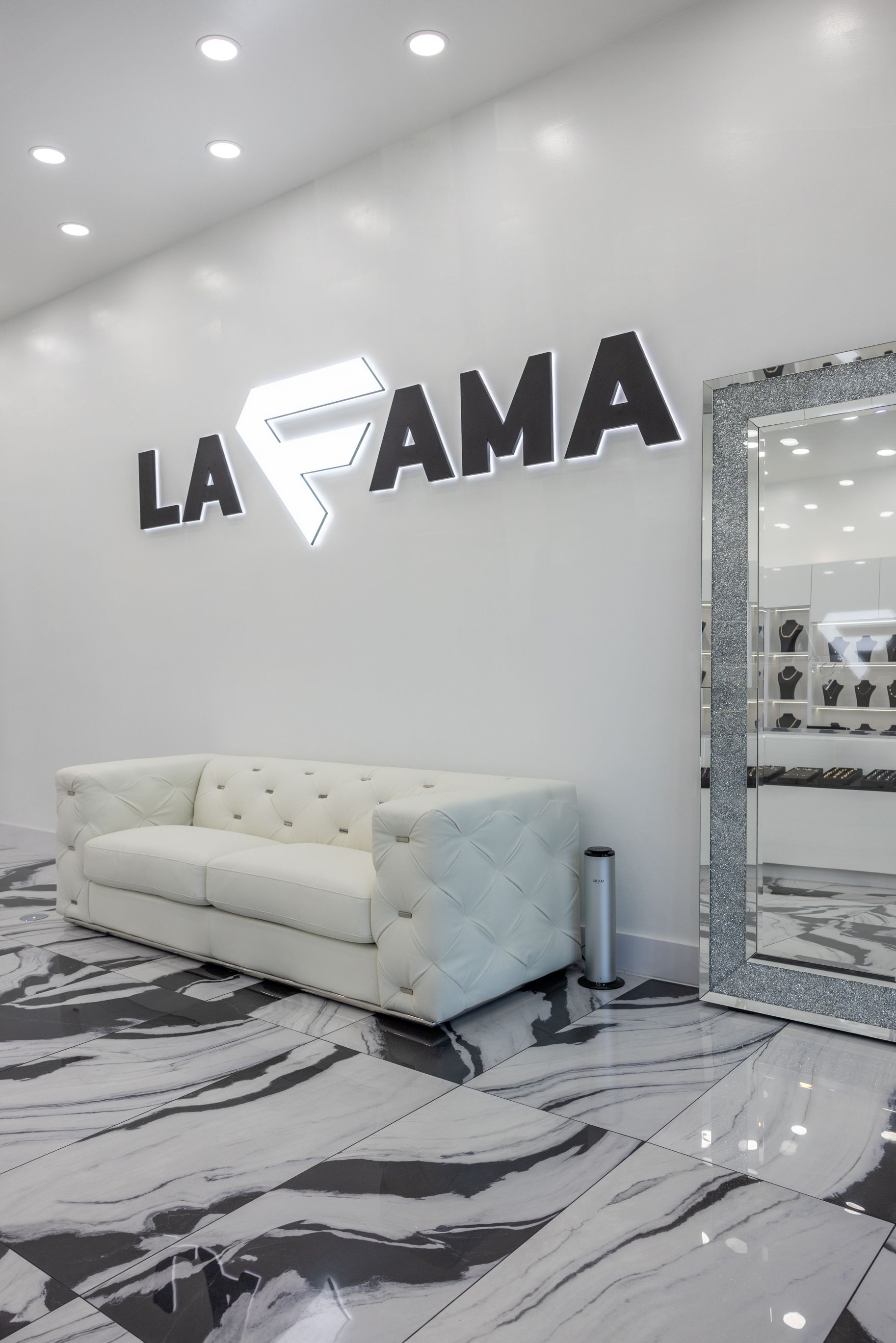 Un sofá blanco está sentado en una habitación al lado de un espejo.