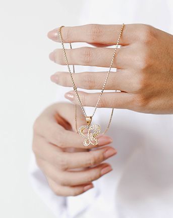Una mujer sostiene un collar con un colgante de mariposa.