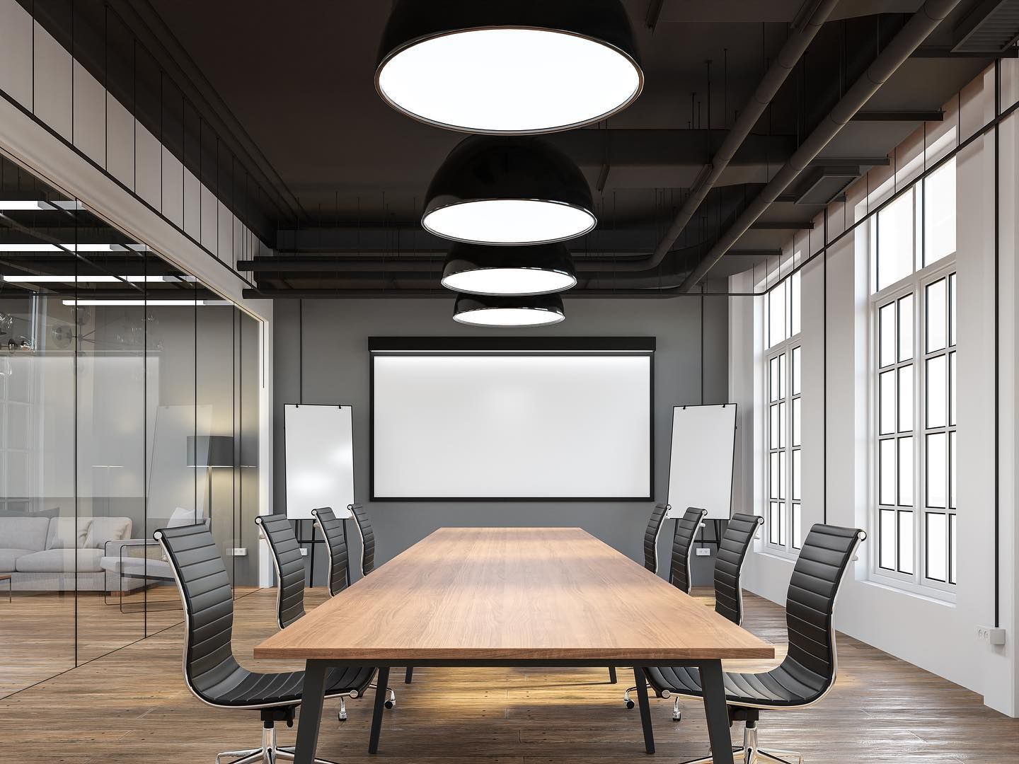 A modern conference room with a long wooden table, black office chairs, large windows, and pendant lights.