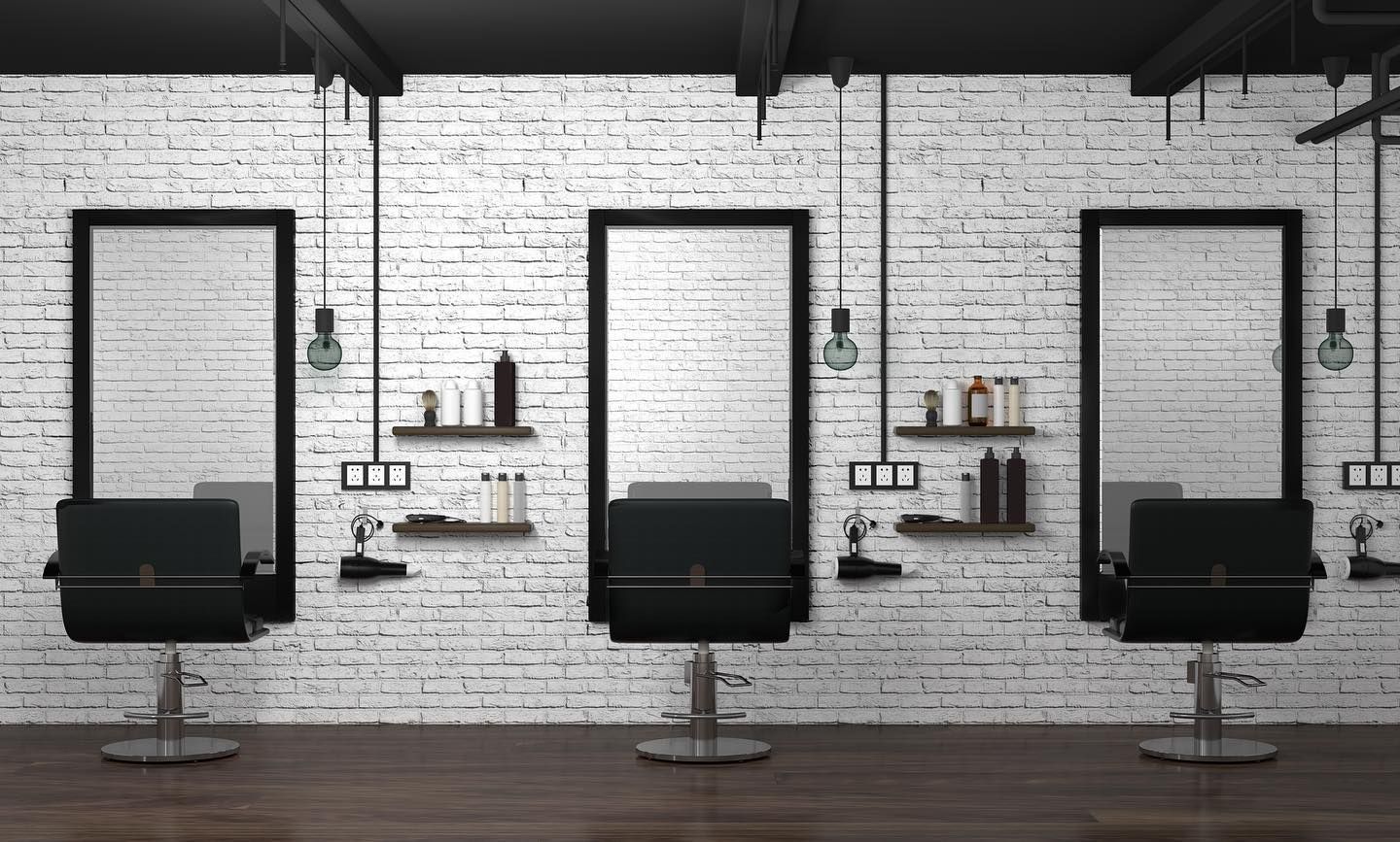 Three salon chairs placed in front of large mirrors against a white brick wall with hanging light fixtures.