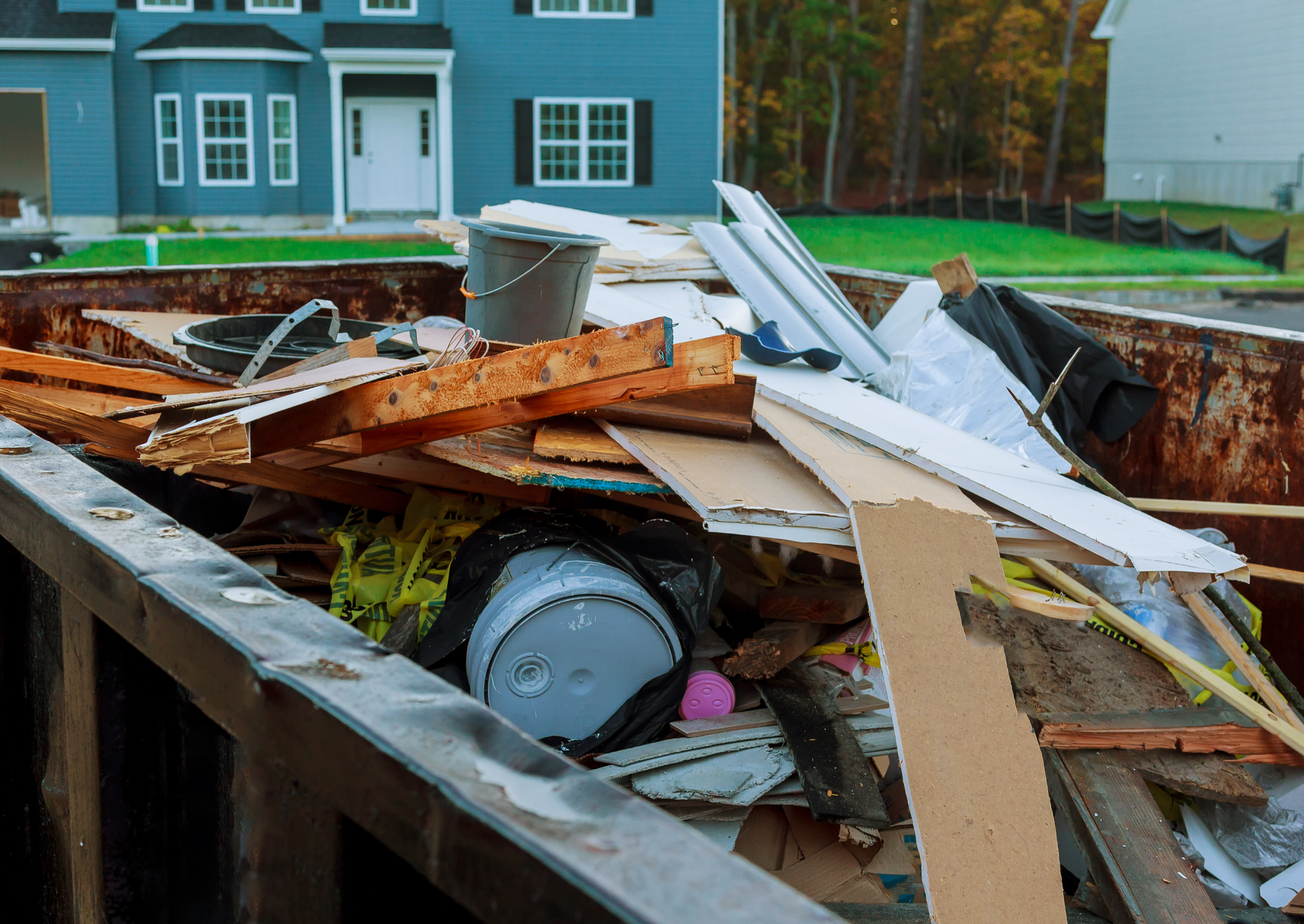 A dumpster filled with junk in front of a house.