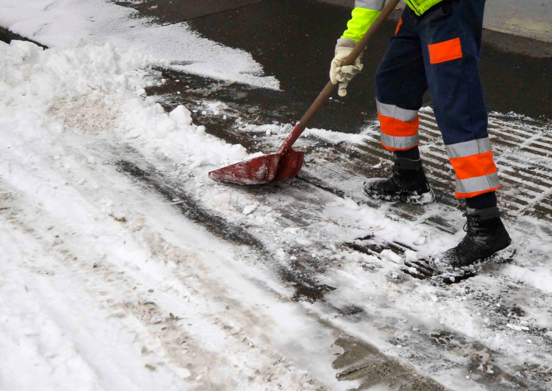 A person is shoveling snow from the sidewalk