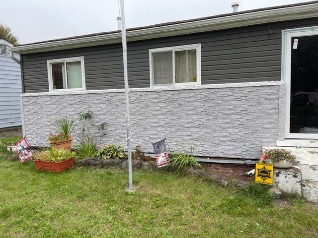 A house with a stone siding and a flag pole in front of it.