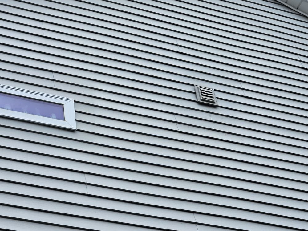 A close up of a gray siding on a house with a window.