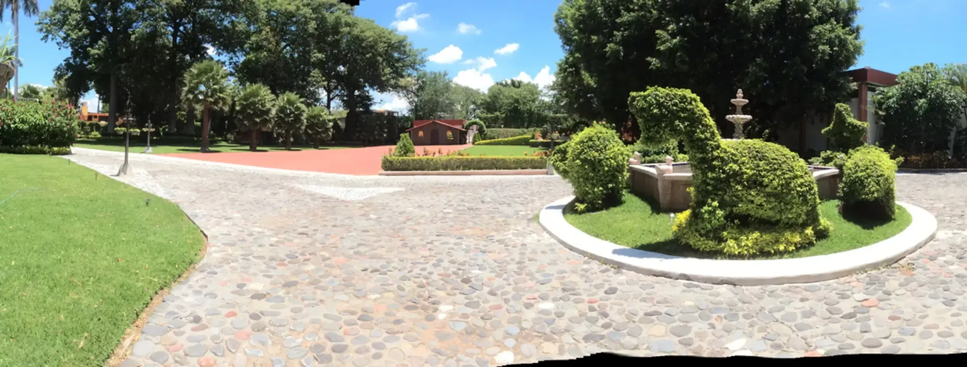 Un camino adoquinado conduce a un exuberante parque verde.