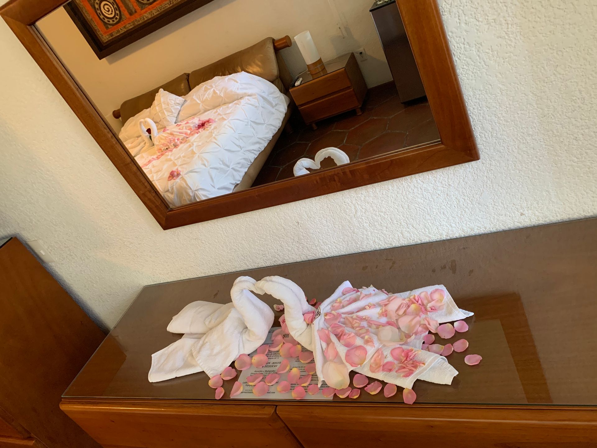 Un dormitorio con un espejo y una mesa con cisnes hechos con toallas.