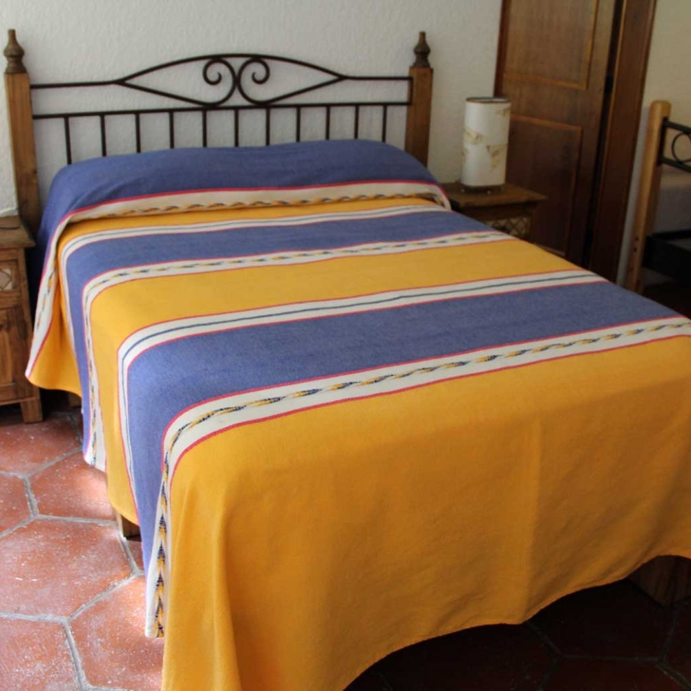 Una cama con una manta de rayas azules y amarillas.