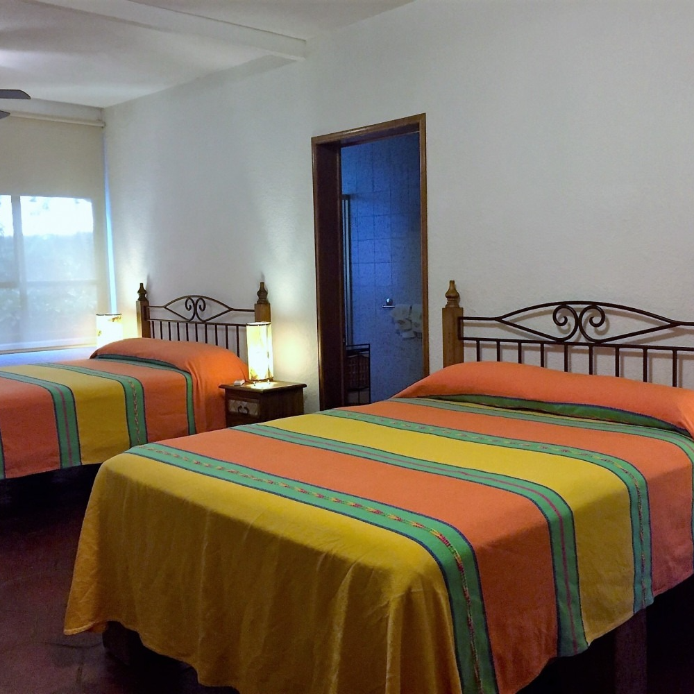 Un dormitorio con dos camas y una puerta que conduce a un baño.