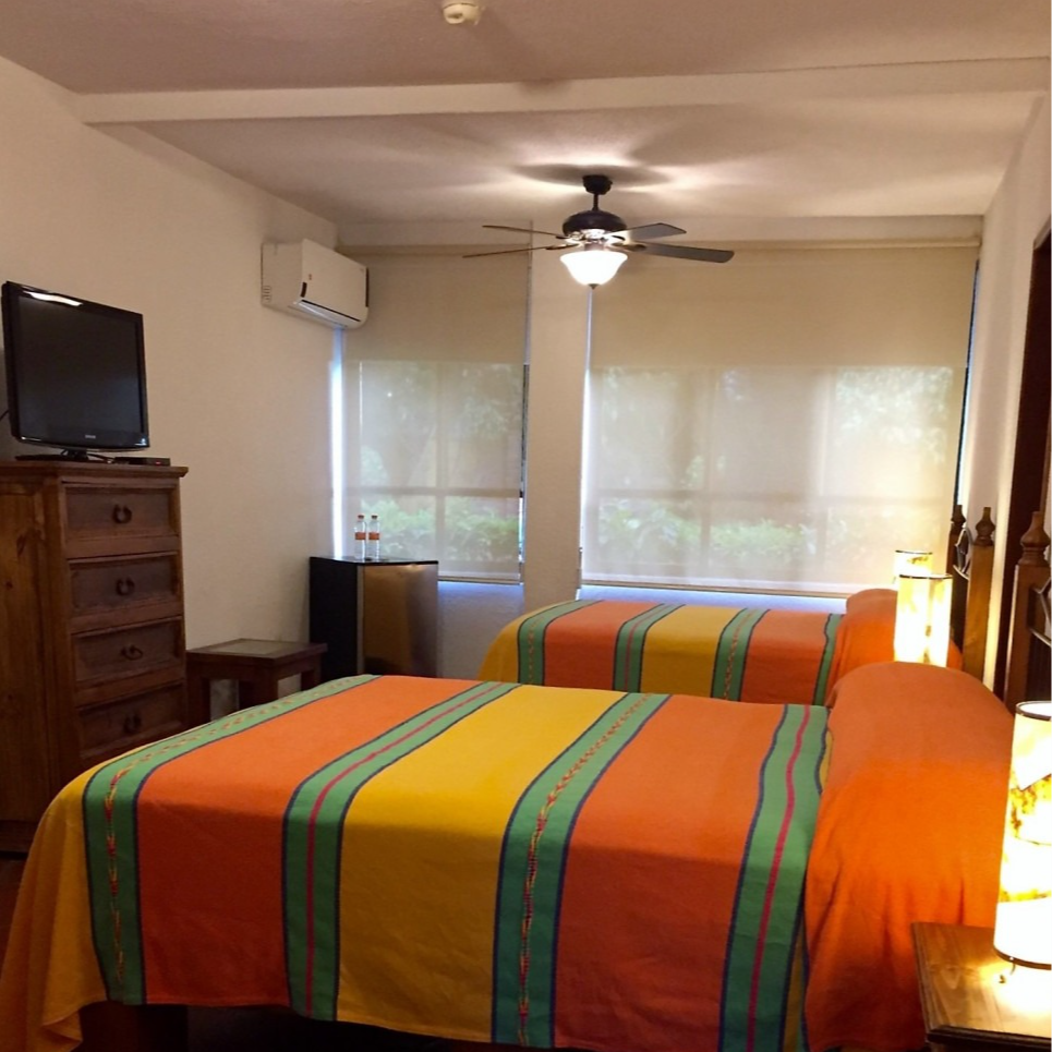 Una habitación de hotel con dos camas y un ventilador de techo.