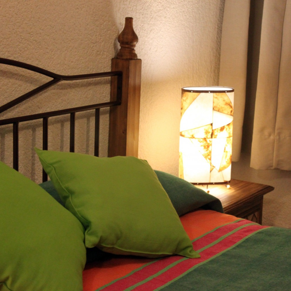 Una cama con almohadas verdes y una lámpara en la mesita de noche.