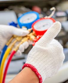 A person wearing a white glove is giving a thumbs up while working on a car.