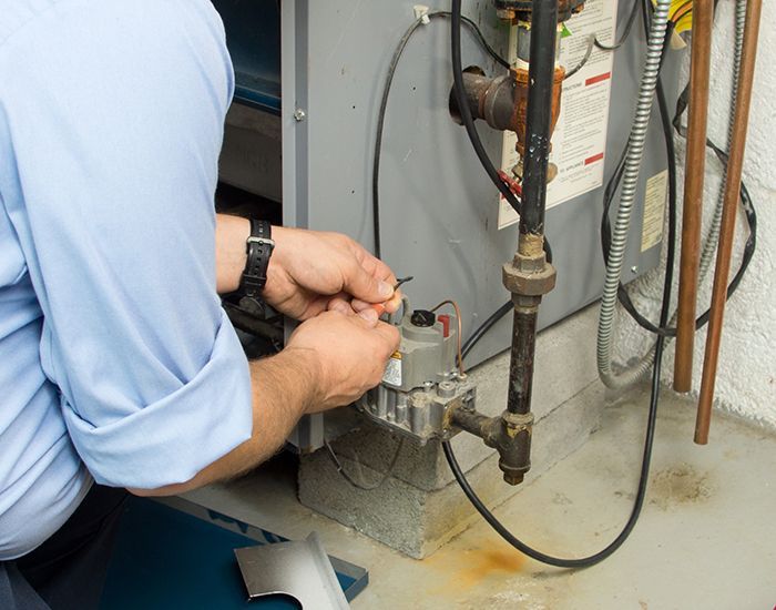 A man in a blue shirt is working on a heater.