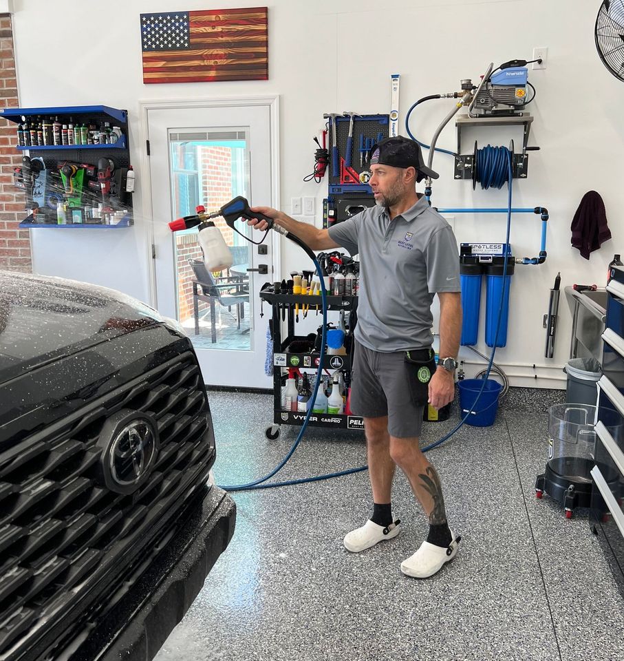 A man is washing a toyota truck in a garage.