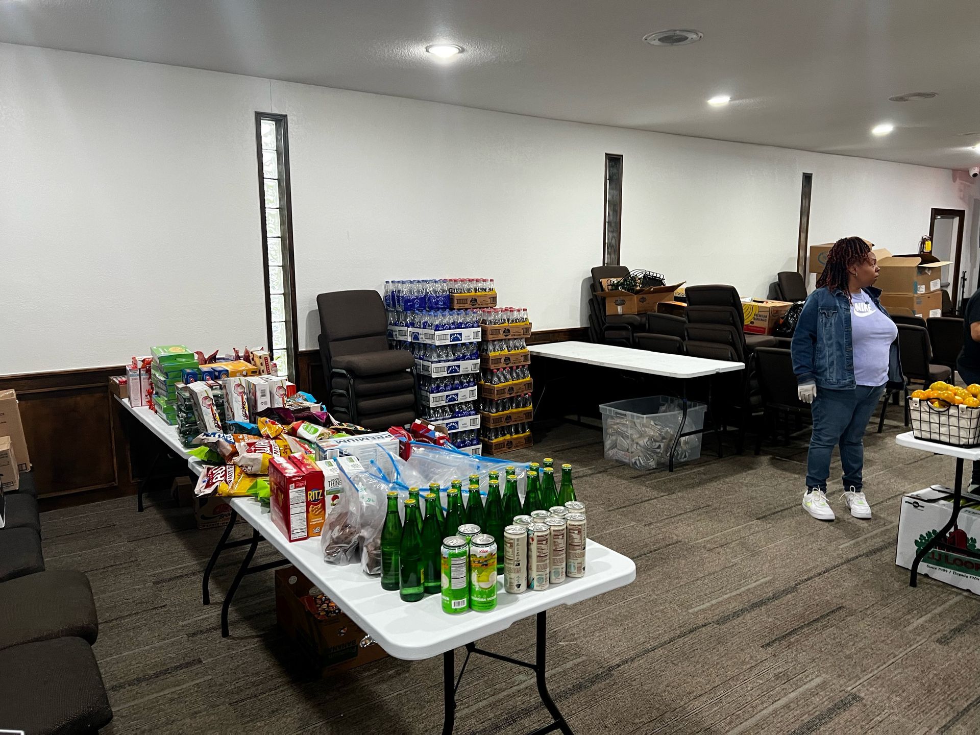 A woman is standing in a room filled with tables and bottles of food. - Lancaster, TX - International Harvest Fellowship Ministries