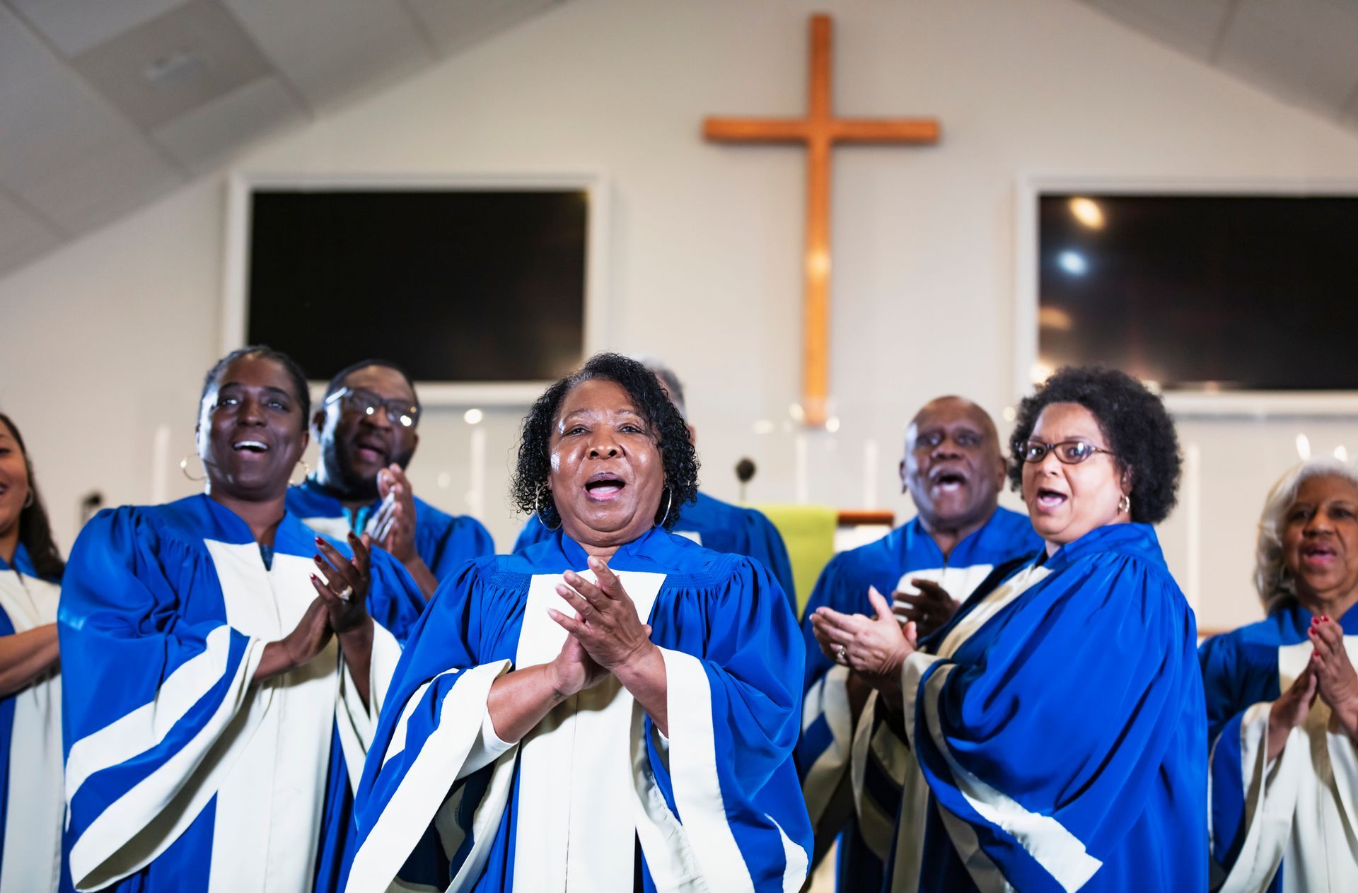 A choir is singing in a church with a cross in the background. - Lancaster, TX - International Harvest Fellowship Ministries