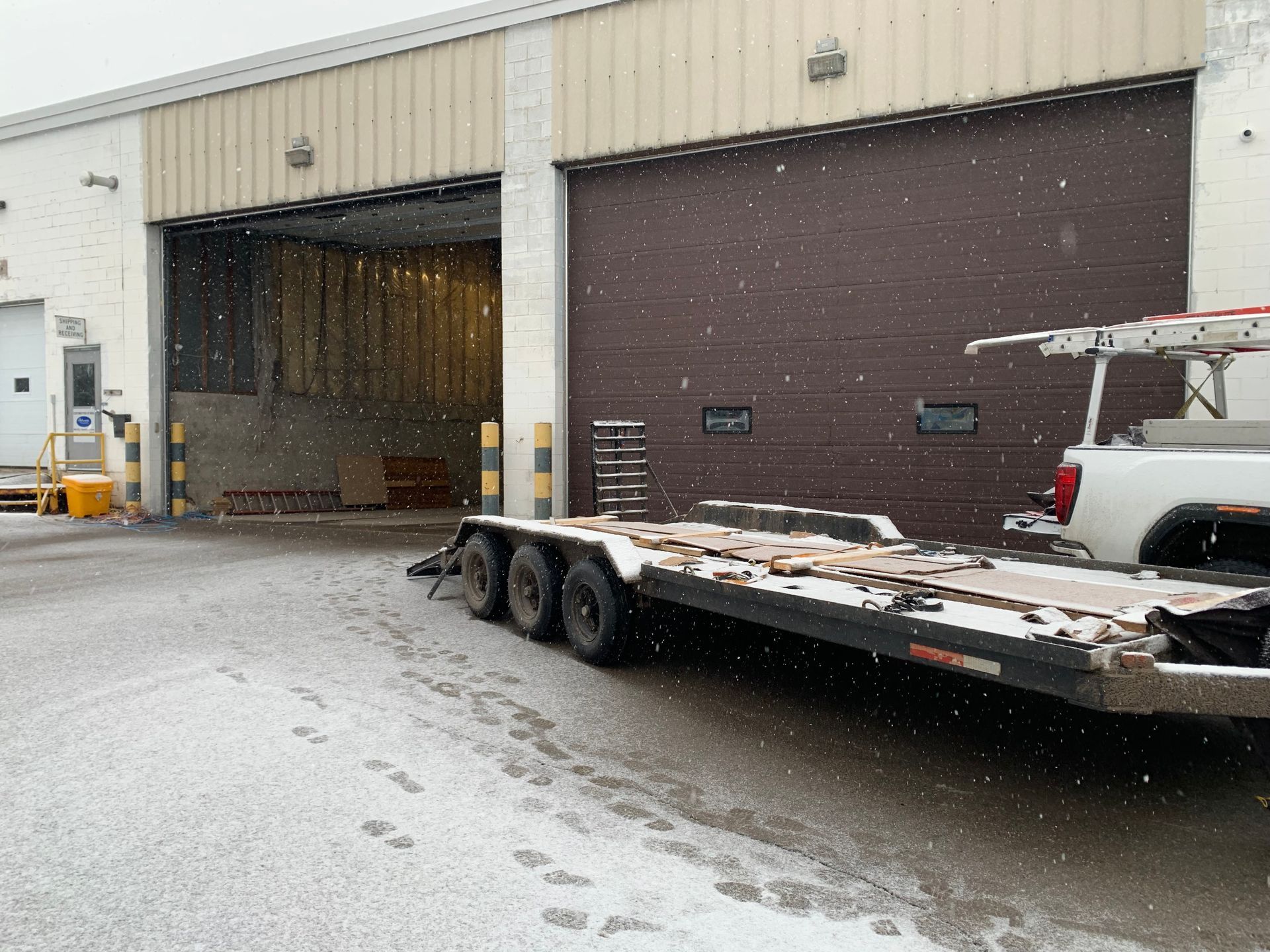 A trailer is parked in front of a building in the snow.