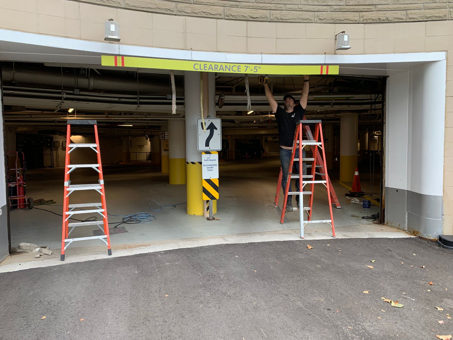 A man on a ladder is working on a garage door