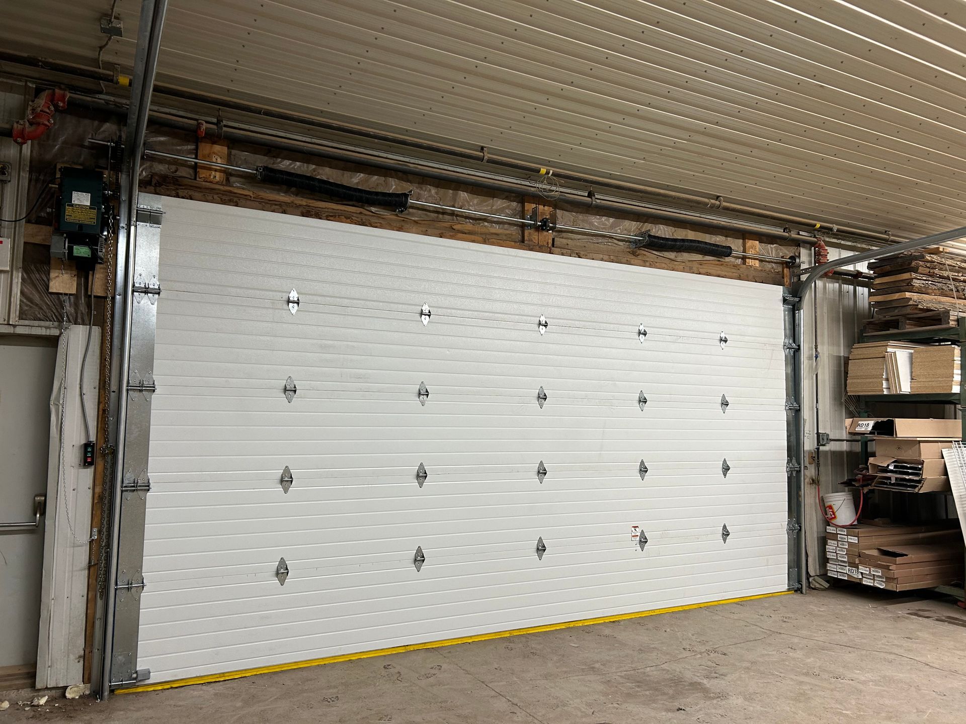 A large white garage door is open in a garage.