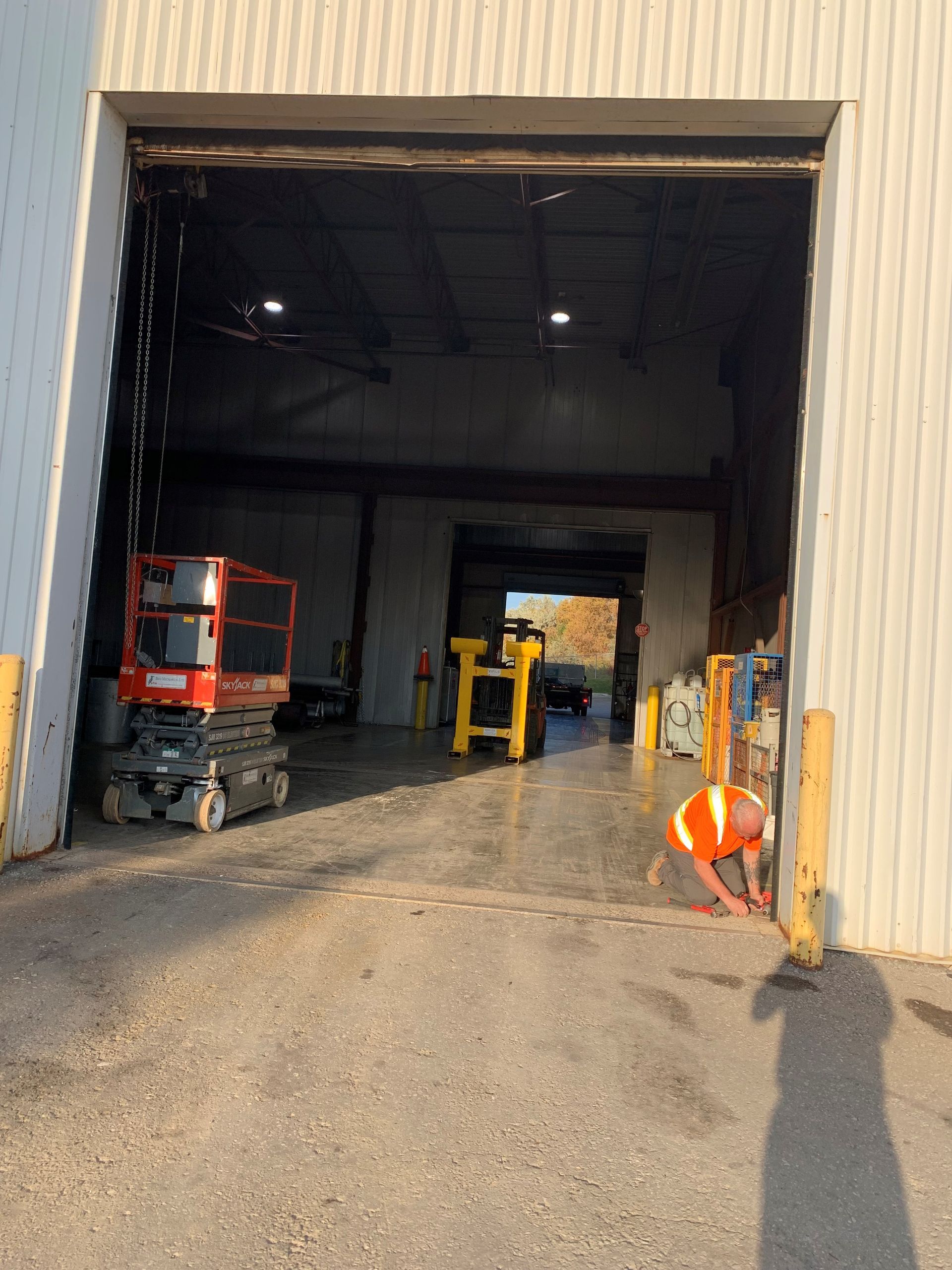 A man is kneeling in front of a large garage door.