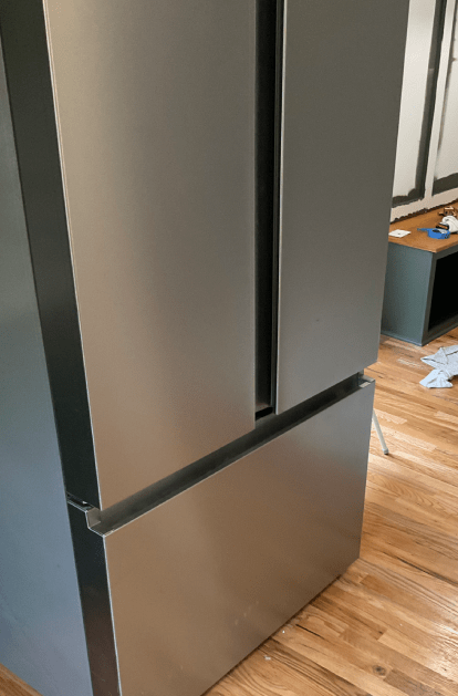 Stainless steel refrigerator in a room with wood flooring.