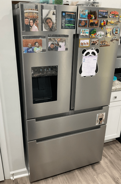 Stainless steel refrigerator with magnets, water dispenser, and lower freezer drawers.